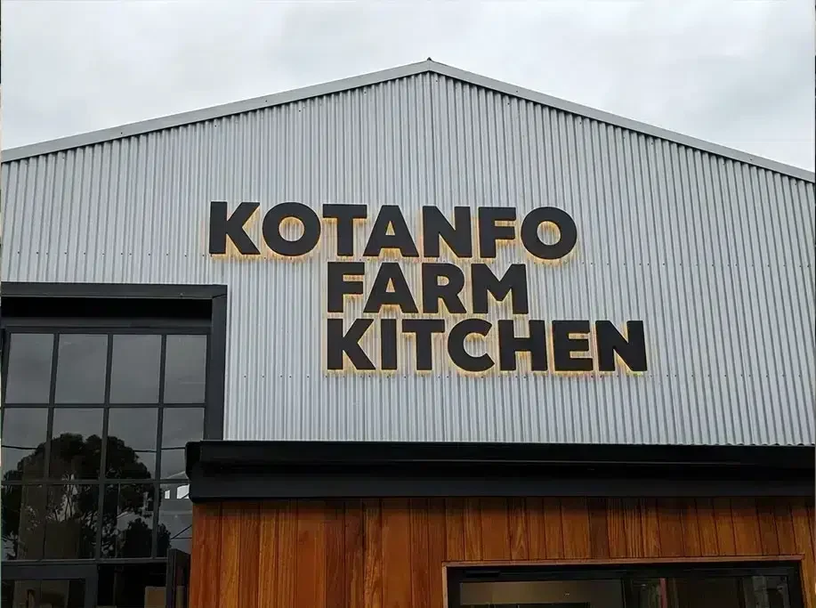Halo-lit fabricated letters on a corrugated façade with glow outlining strokes and counters